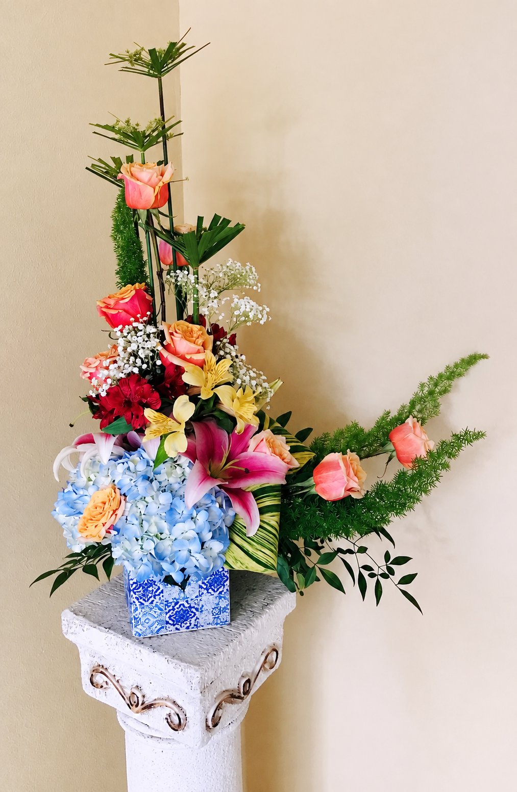 Blue Horizon Garden floral arrangement photographed on a stone pedestal, showing its tall stems and blue patterned vase